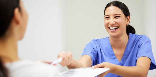 A dental hygienist handing some documents to a patient