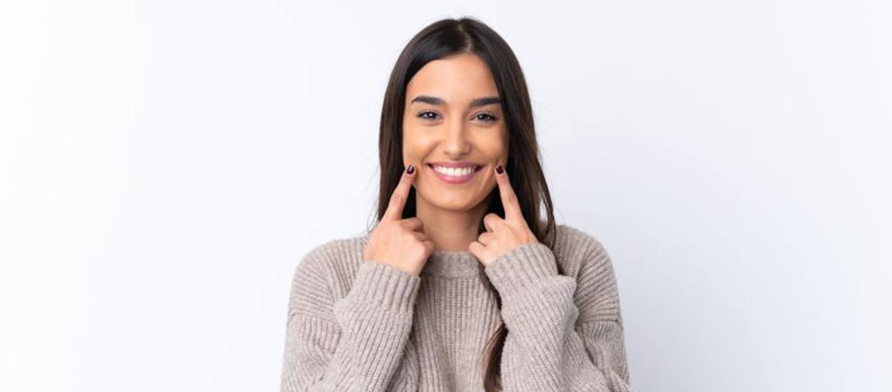 Happy young woman pointing at her teeth
