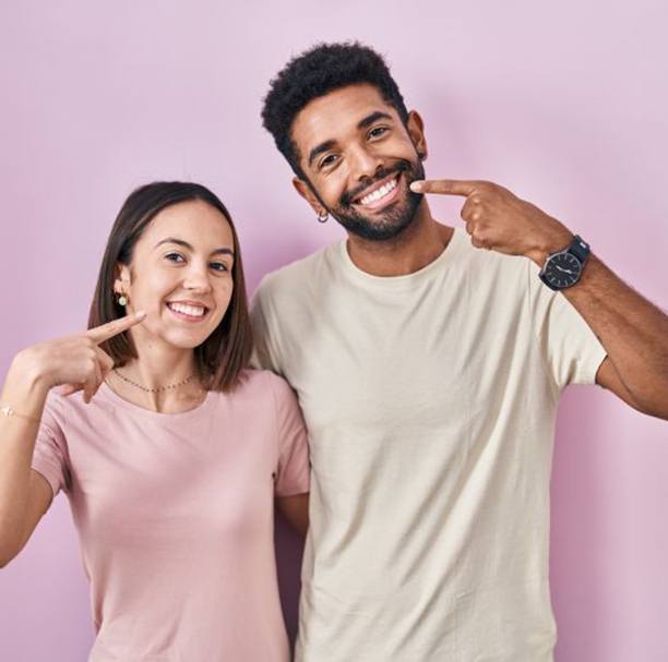 Young couple pointing at their teeth