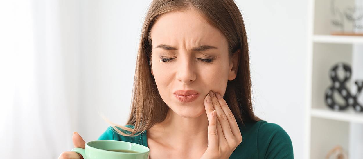 woman holding coffee wincing in pain