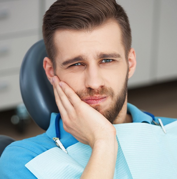 man with beard holding cheek in pain