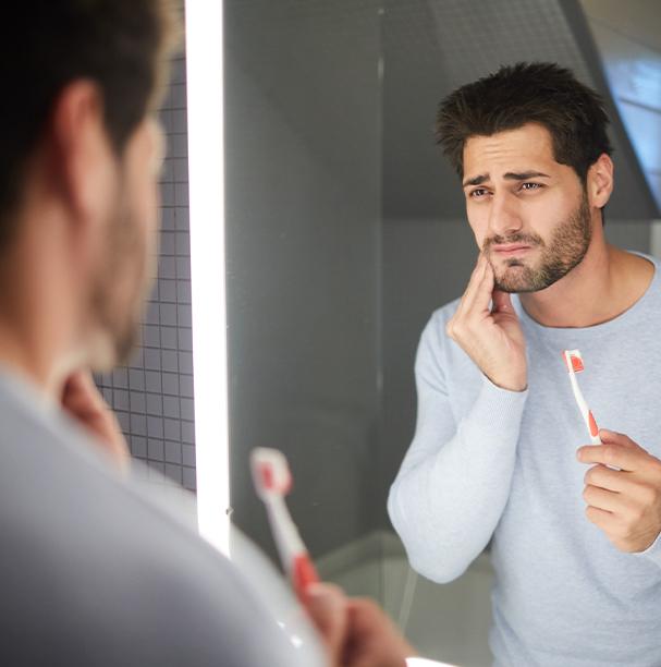 man holding toothbrush in pain