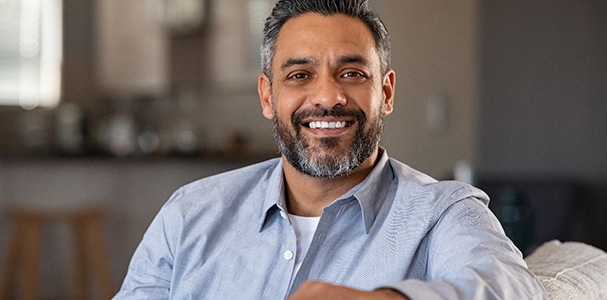 Man in blue button-up smiling on couch