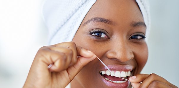 Woman smiling while flossing in bathroom