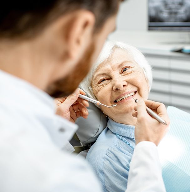 older woman smiling up at dentist