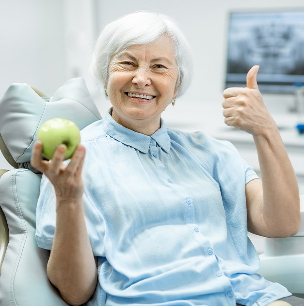 woman doing thumbs up holding apple