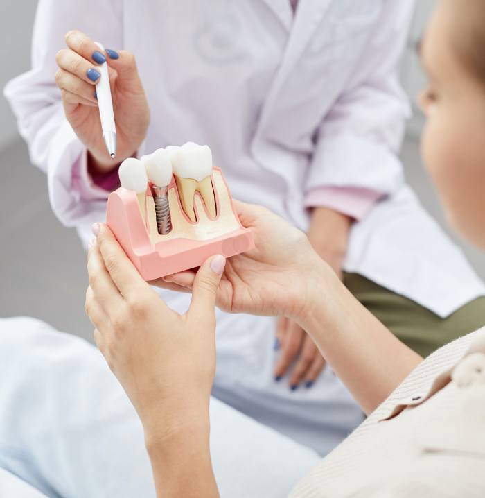 Dentist pointing to dental implant mockup