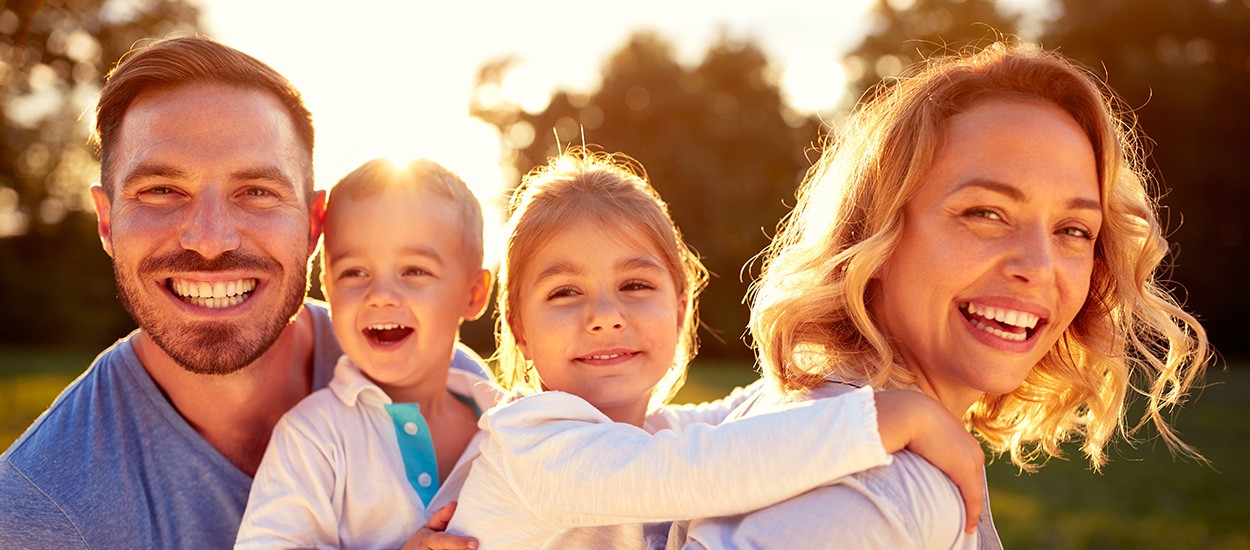 family of four smiling in sunlight