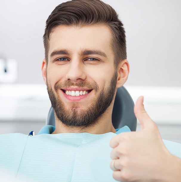 man in exam chair doing thumbs up