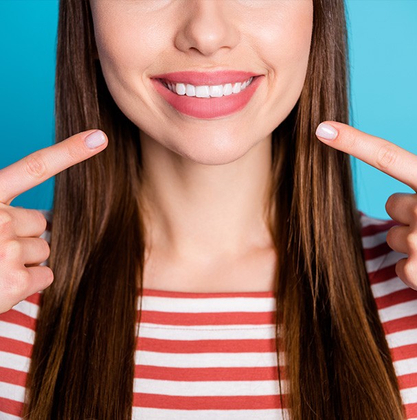 woman in striped shirt pointing to smile