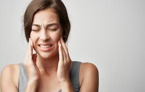 woman experiencing jaw pain, clenched teeth and white background