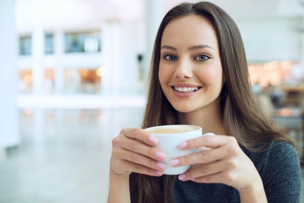 person smiling and holding cup of coffee